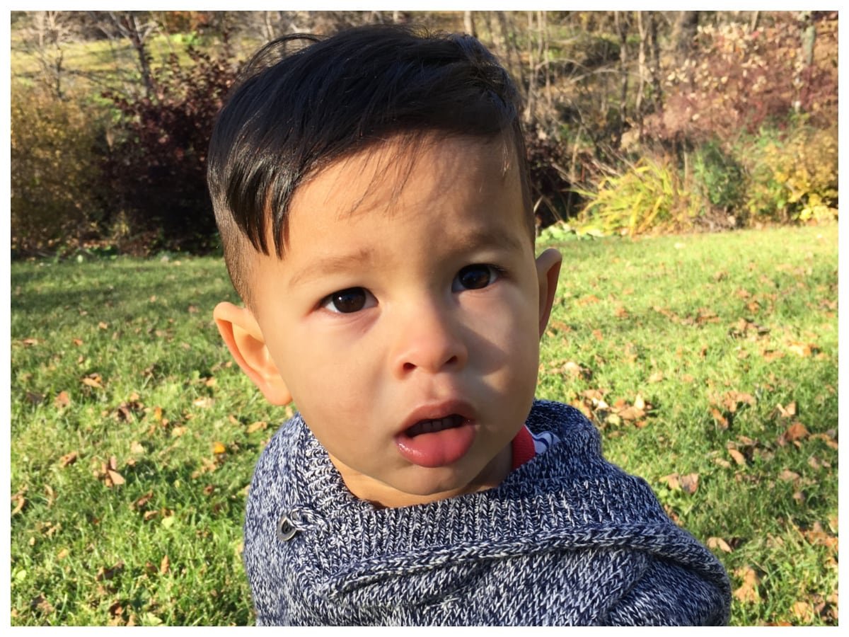 default-169 A boy sits outside on the grass and looks questioningly at the camera.
