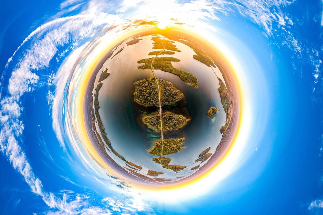 An orb resembling a planet surrounded by an orange ring features a roadway connecting multiple islands