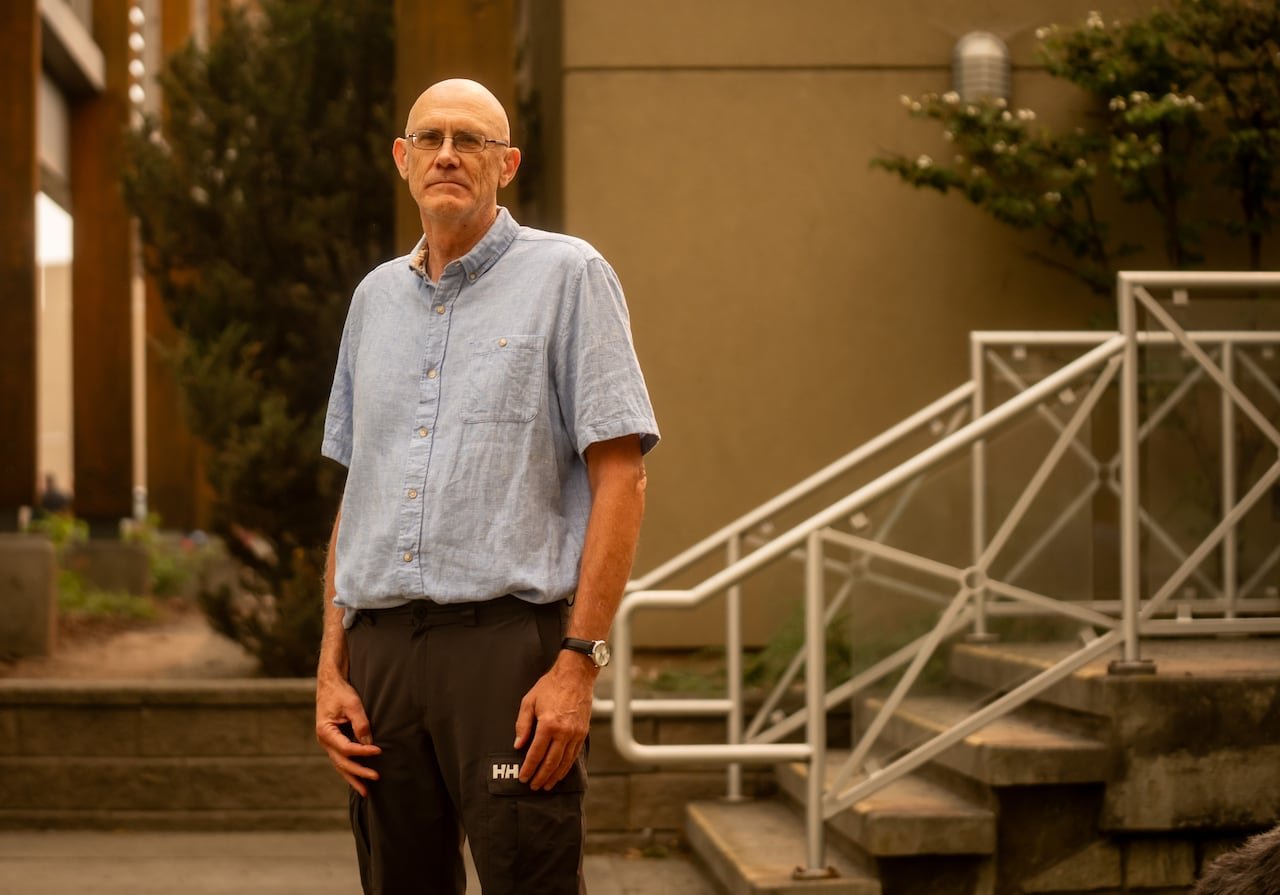 A bald man in a blue shirt amidst smoky air.