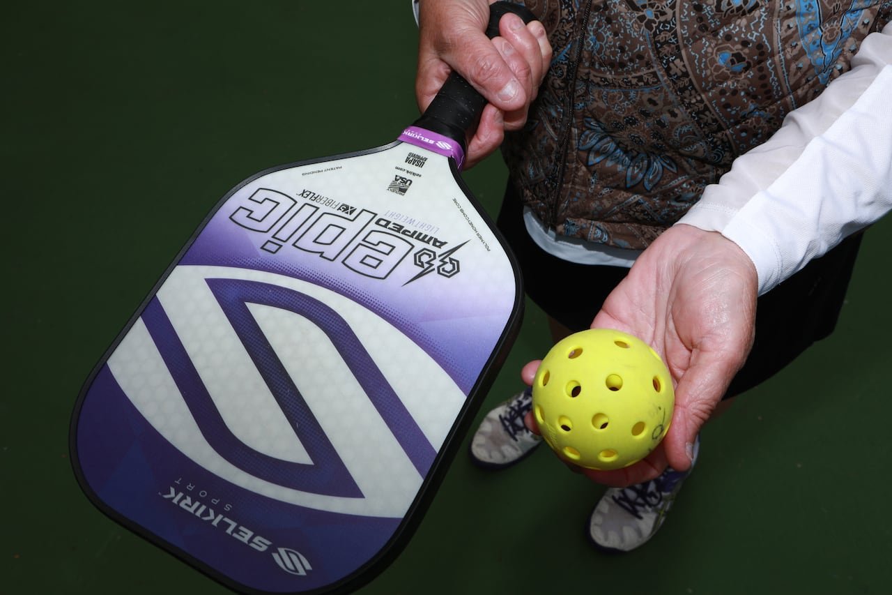 default-536 Close up photo of a pickleball paddle and ball in a woman's hands.